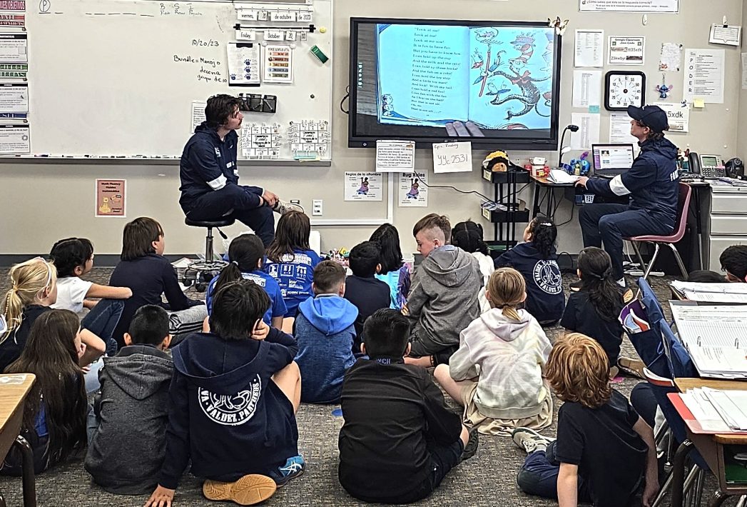 Five photos of college athletes speaking to elementary school students in their classroom.