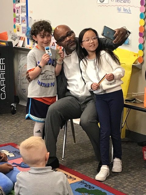 Mayor Michael Hancock taking selfies with students in a classroom.