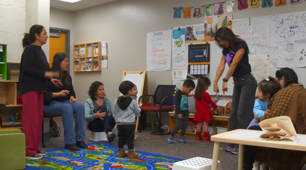 Photo of a teacher, parents, and students in a classroom.