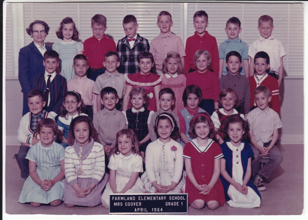 Vintage classroom photo of students and teacher on beige carpet.