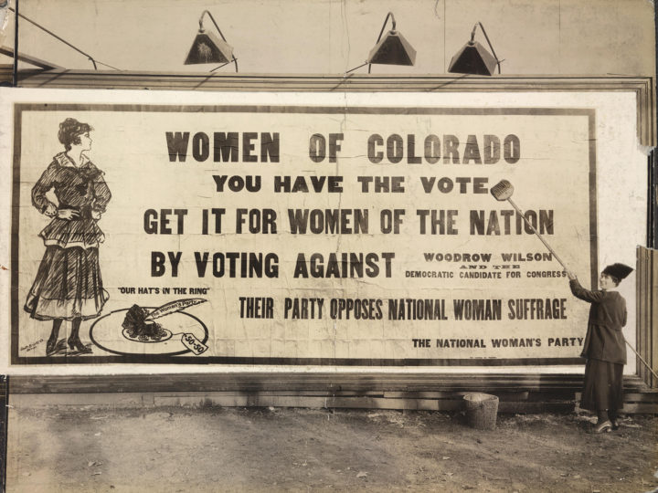 Photo of a billboard in Denver in 1916 that says, "Women of Colorado, You have the vote. Get it for women of the nation by voting against Woodrow Wilson. Their party opposes National Women Suffrage."