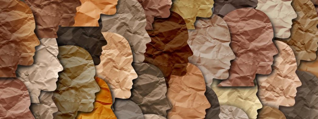 Image a collage of silhouettes of heads/faces cut out from different colors of paper to represent different flesh tones.