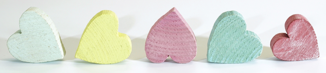 Green, yellow, and pink wooden hearts on a white background