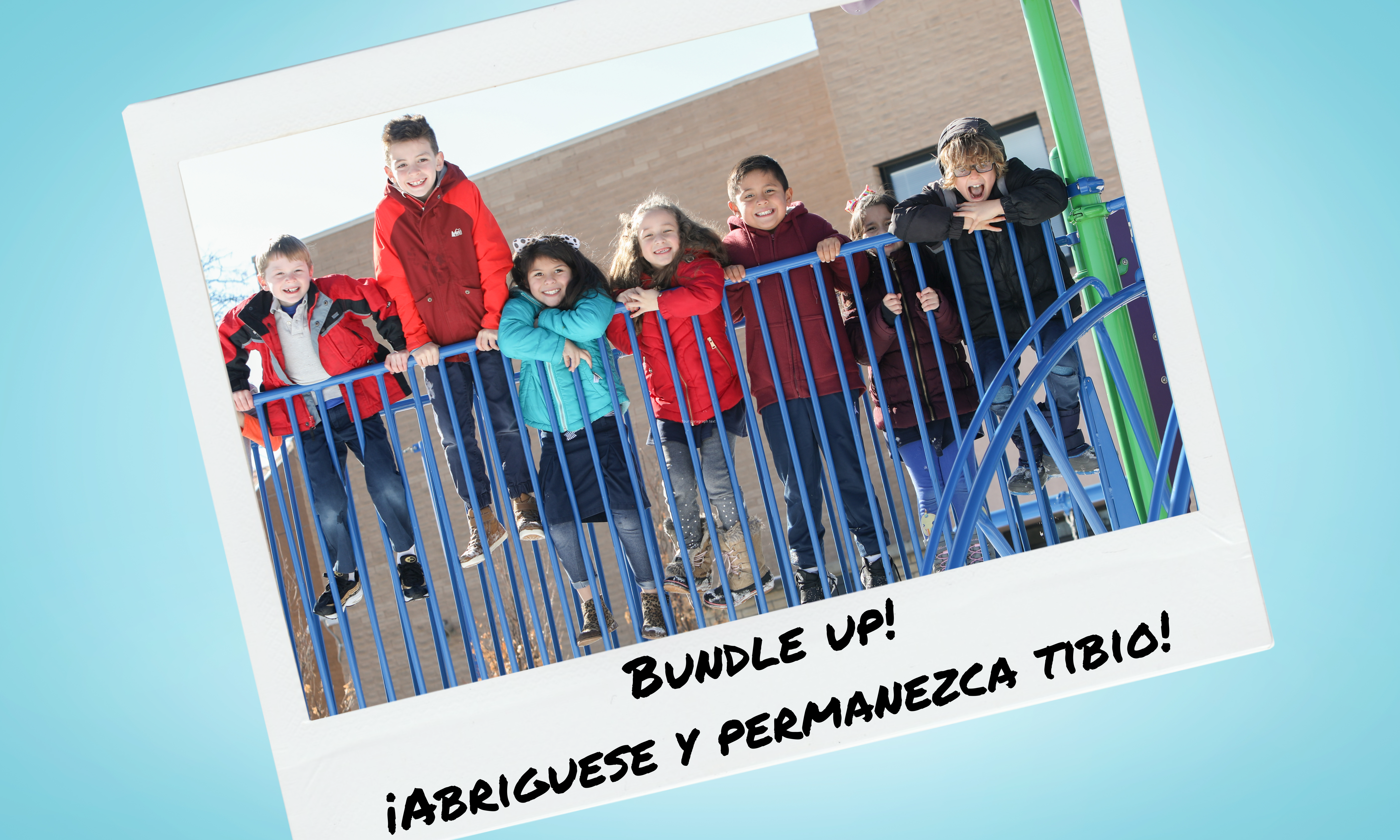 Photo of students in winter coats on playground equipment in a frame that looks like a Polaroid picture. Written under the picture in black ink is "Bundle up! / ¡Abriguese y permanezca tibio!