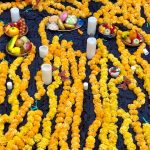 Garlands of yellow marigolds surrounding several candles and offerings for Day of the Dead.